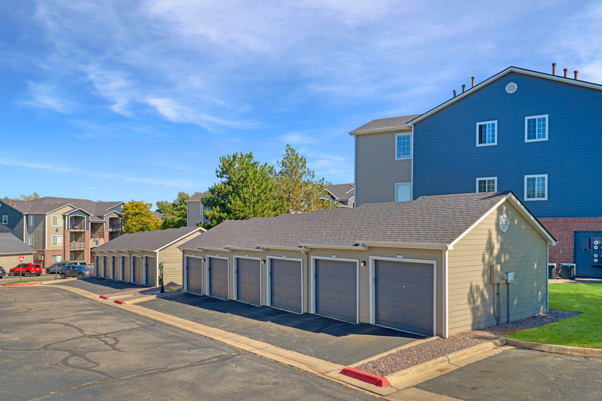 The building's exterior surrounded by a lush green landscape at The Crossings at Bear Creek Apartments in Lakewood, Colorado