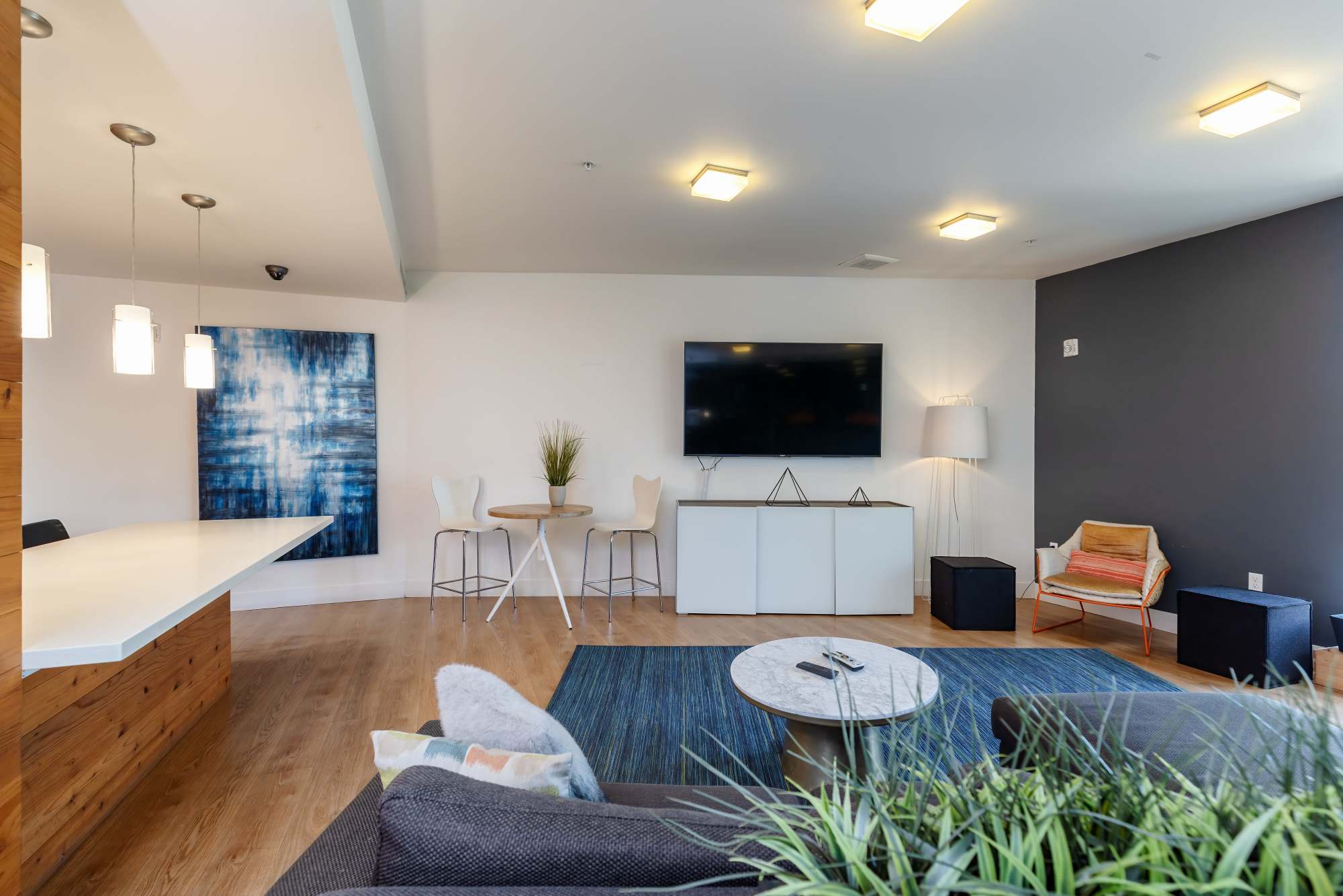 A modern community lounge with a large TV, sofa, coffee table and large windows atThe Union in Portland, Oregon