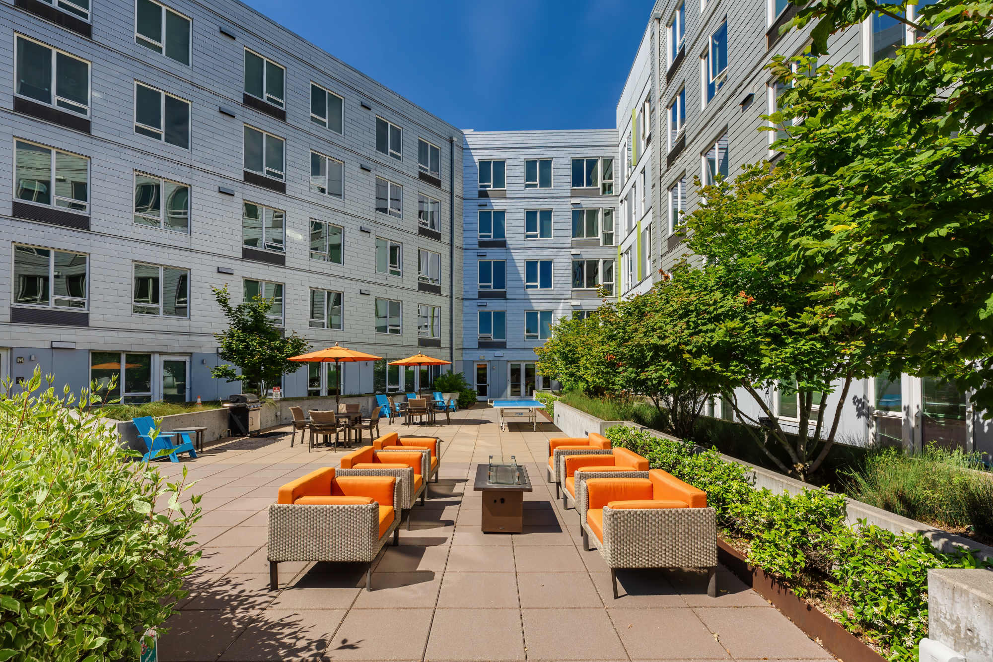 A patio with furniture, trees, multiple seating and a fire pit at The Union in Portland, Oregon