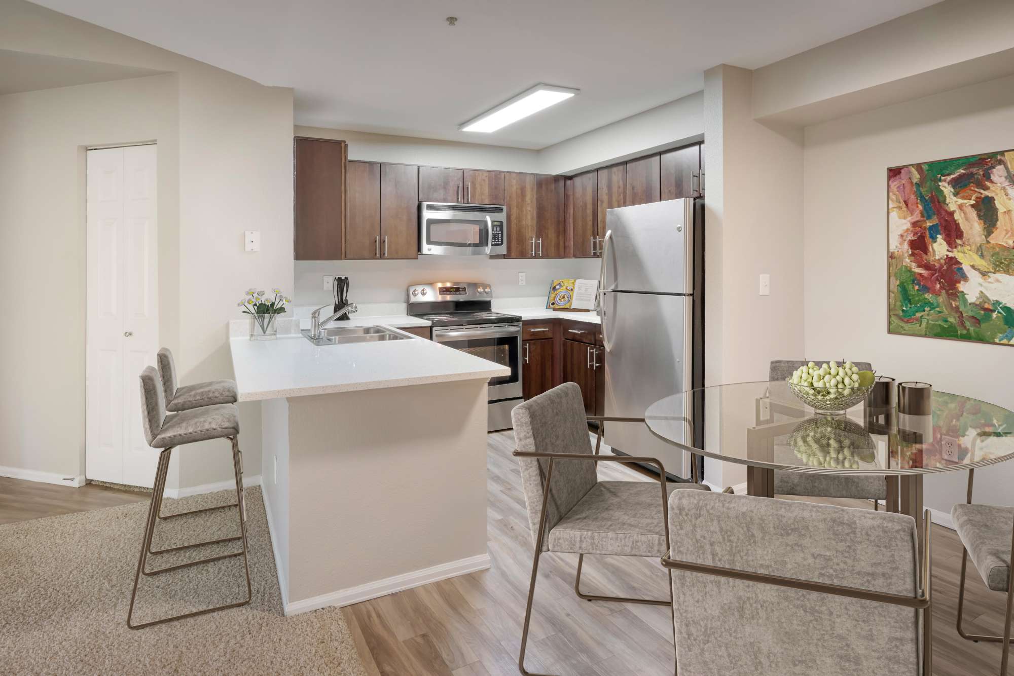 A renovated kitchen with brown cabinets and a breakfast bar at The Crossings at Bear Creek Apartments in Lakewood, Colorado