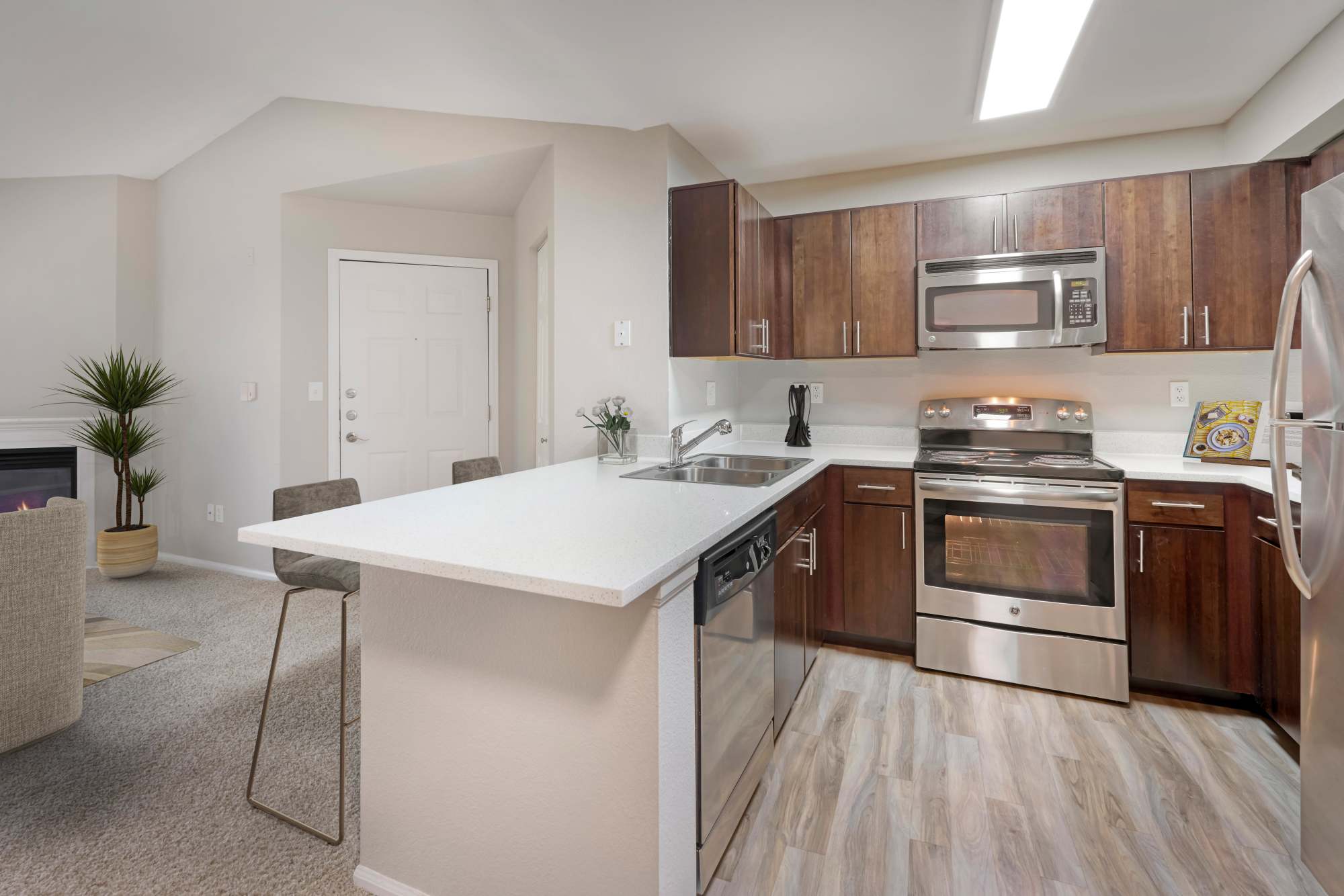 A renovated kitchen with brown cabinets and stainless steel appliances at The Crossings at Bear Creek Apartments in Lakewood, Colorado