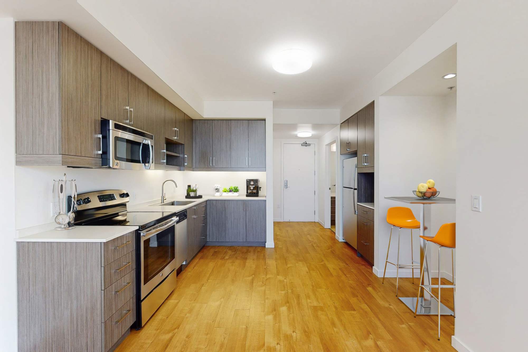 View of the kitchen with stainless-steel appliances, hardwood floors and white walls atThe Union in Portland, Oregon