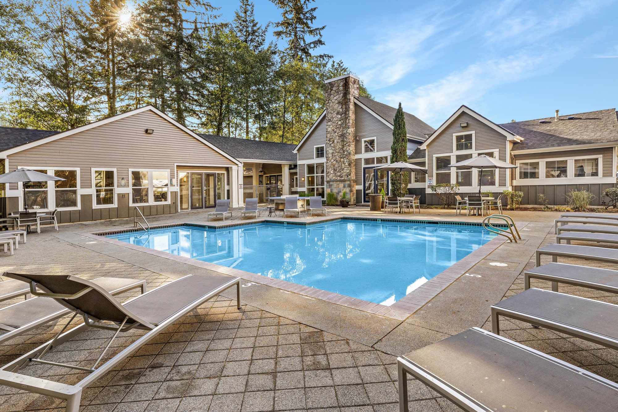 The community pool and spa with lounge chairs at Wildreed Apartments in Everett, Washington