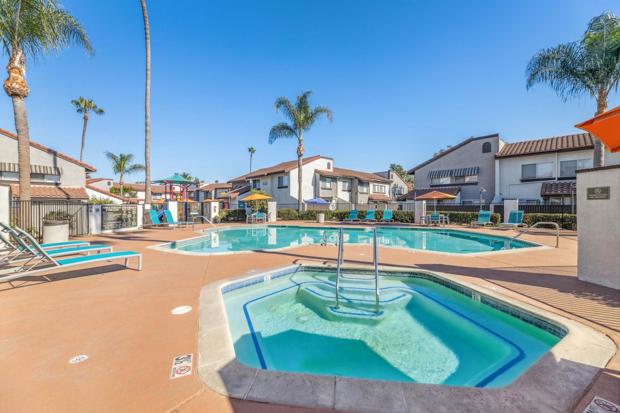 Tables and chairs with umbrellas next to the grilling station at Portofino Townhomes in Wilmington, California