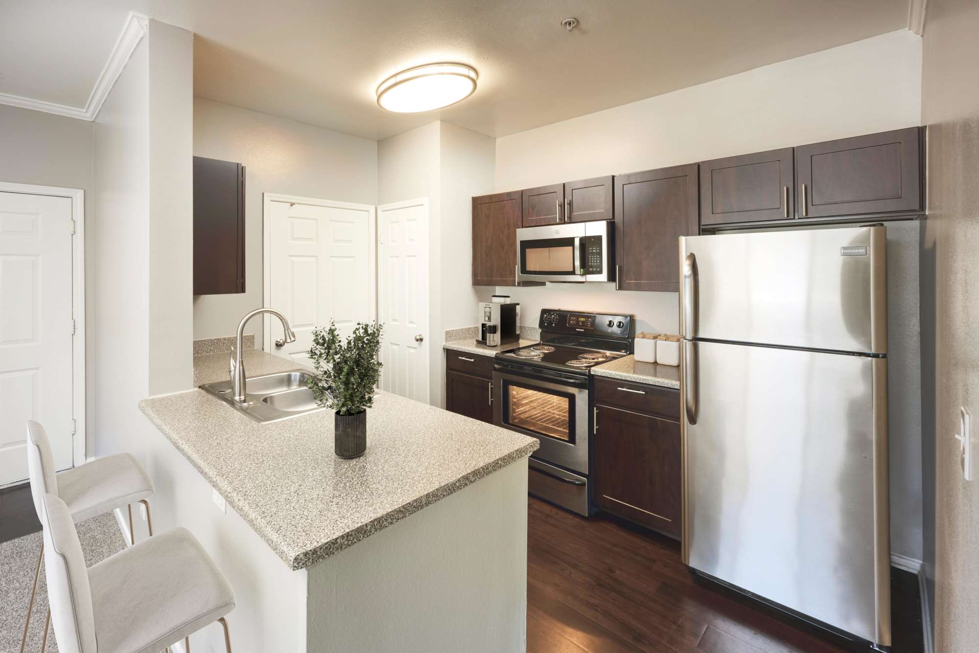 Espresso-colored cabinetry and granite countertops on display in this kitchen at Hawthorne Hill Apartments in Thornton, Colorado