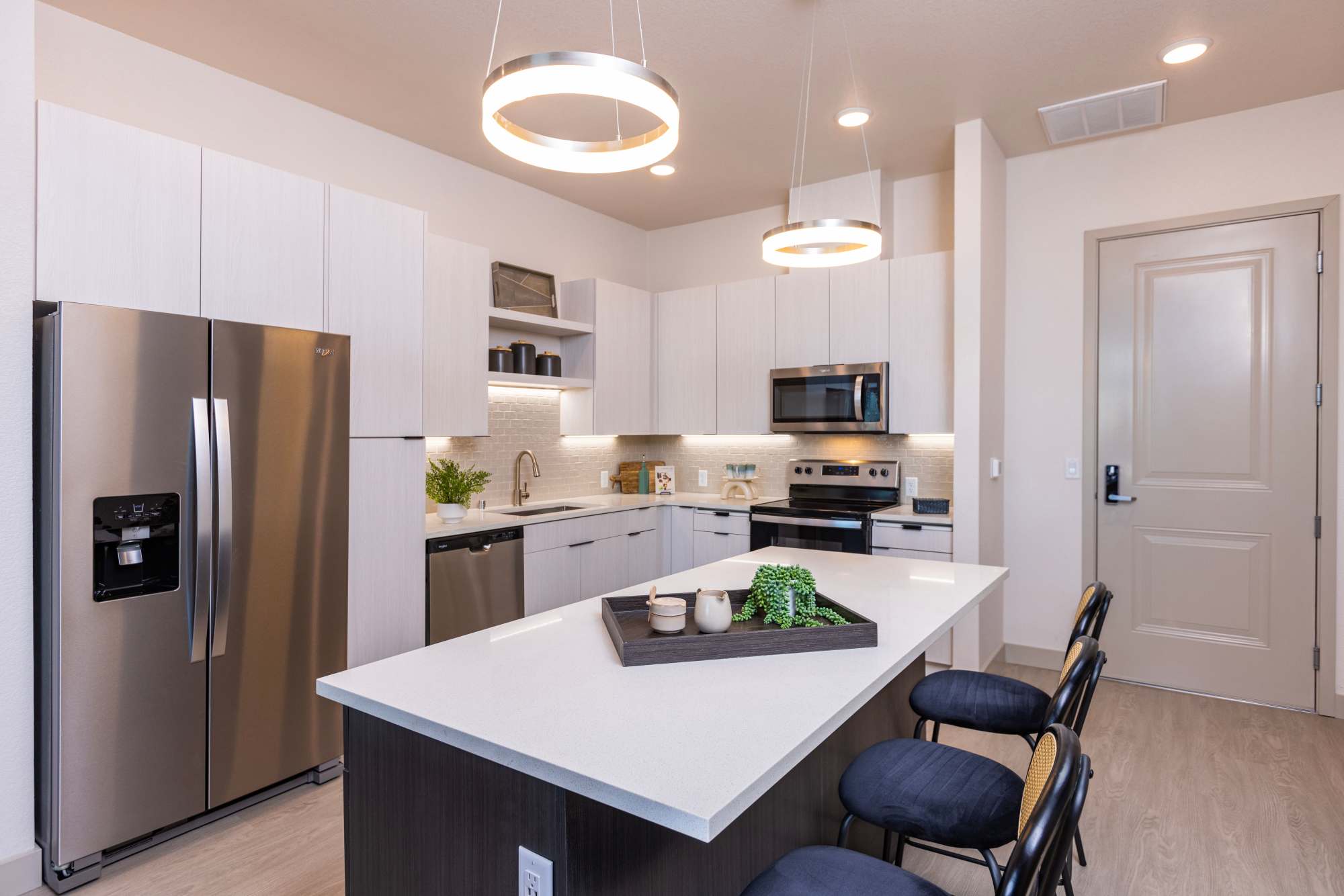 Kitchen with island and stools, refrigerator, stove, and wood cabinetry at Zeta Luxury Apartments in Sacramento, California