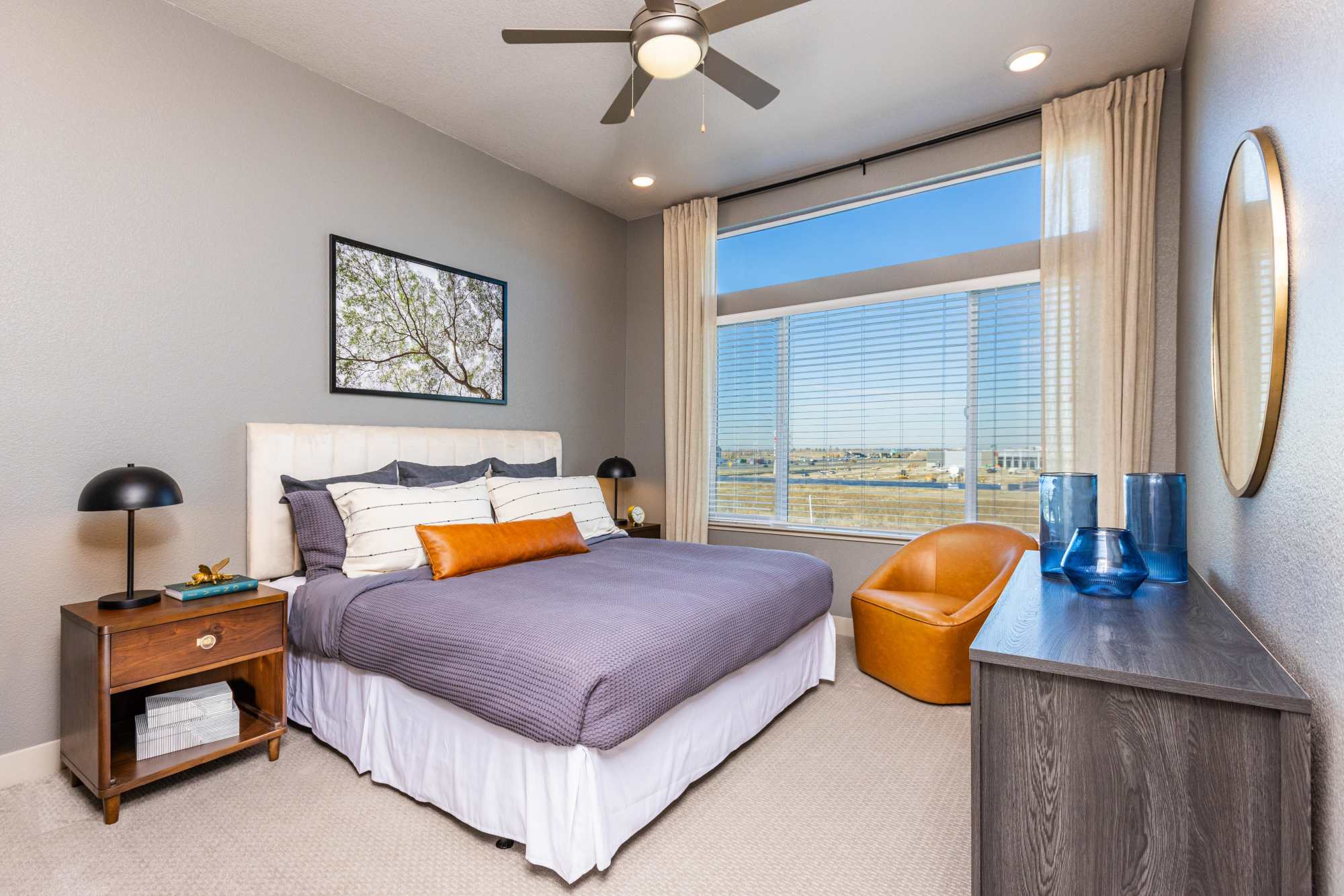 Well-lit bedroom with ceiling fan and large window at Zeta Luxury Apartments in Sacramento, California