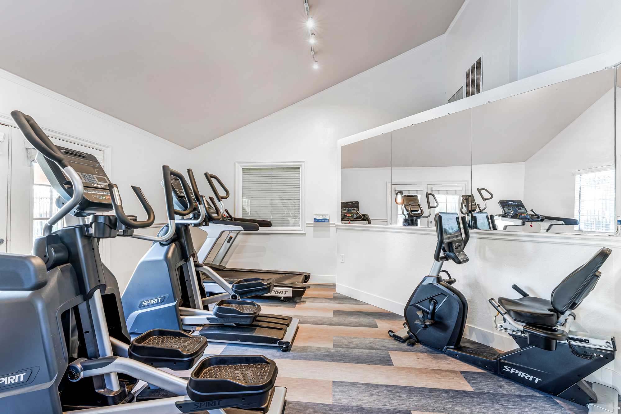 Fitness center with cardio machines looking through large windows to pool at Shadow Ridge Apartments in Oceanside, California