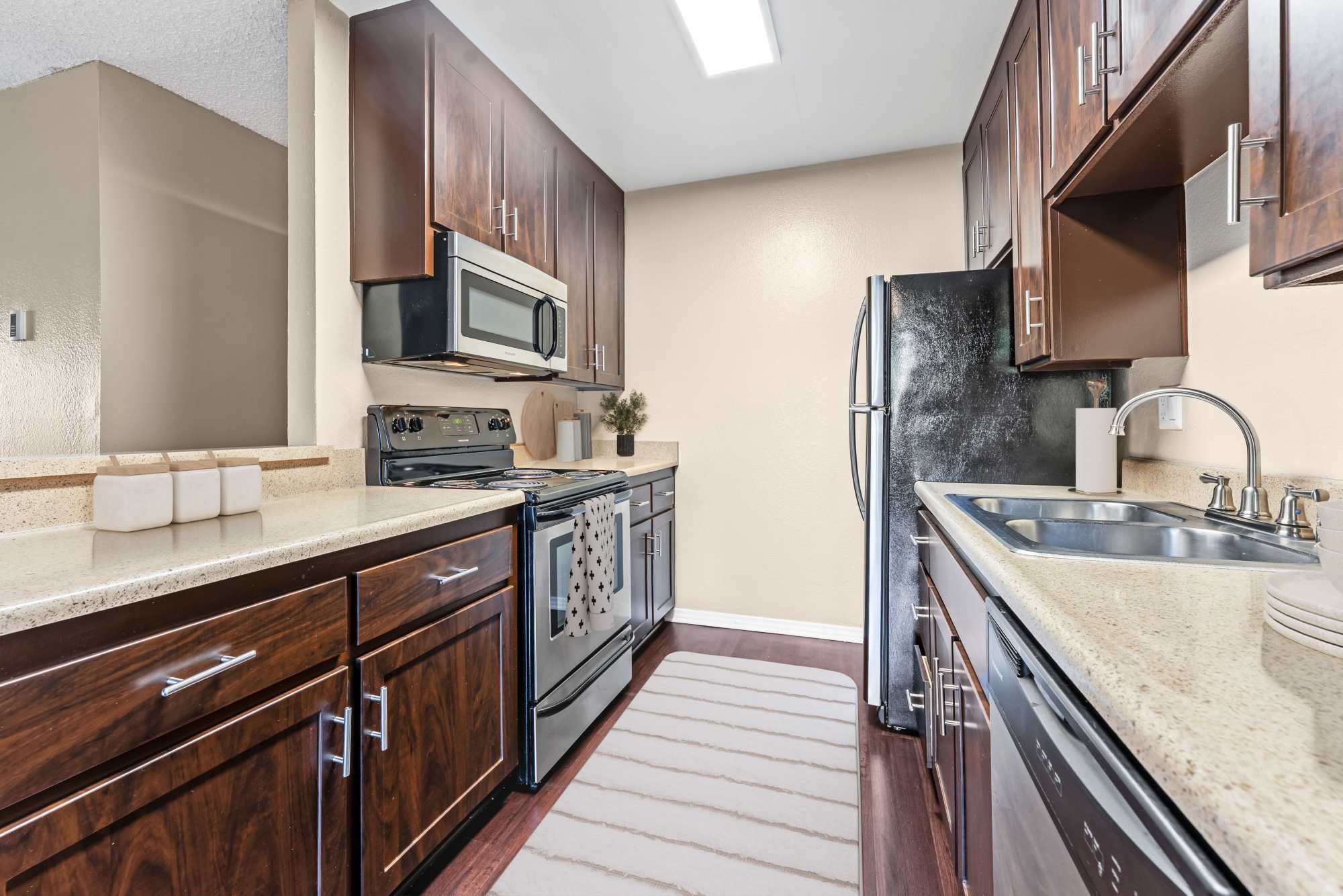Espresso cabinets renovated kitchen with stainless steel appliances at Shadow Ridge Apartments in Oceanside, California