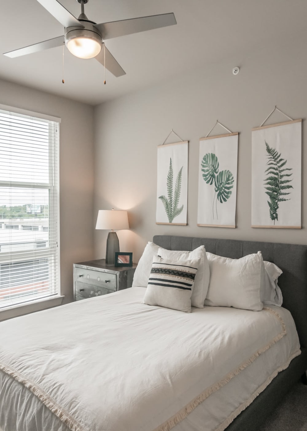 2-Bedroom Apartments in Capital View, TN - The Guthrie North Gulch - Furnished Bedroom with a Bed, a Chair, a Nightstand, a Large Window, a Ceiling Fan, Stylish Decor, and Carpet Flooring