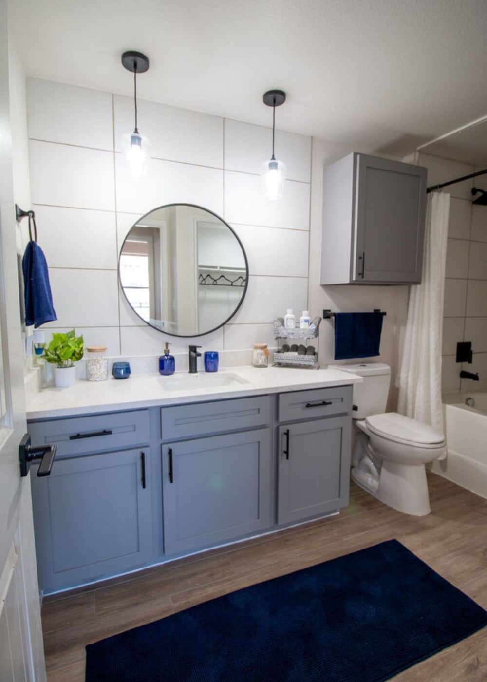 An apartment bathroom with modern light finishes and a round mirror at Legends Lakeline in Austin, Texas