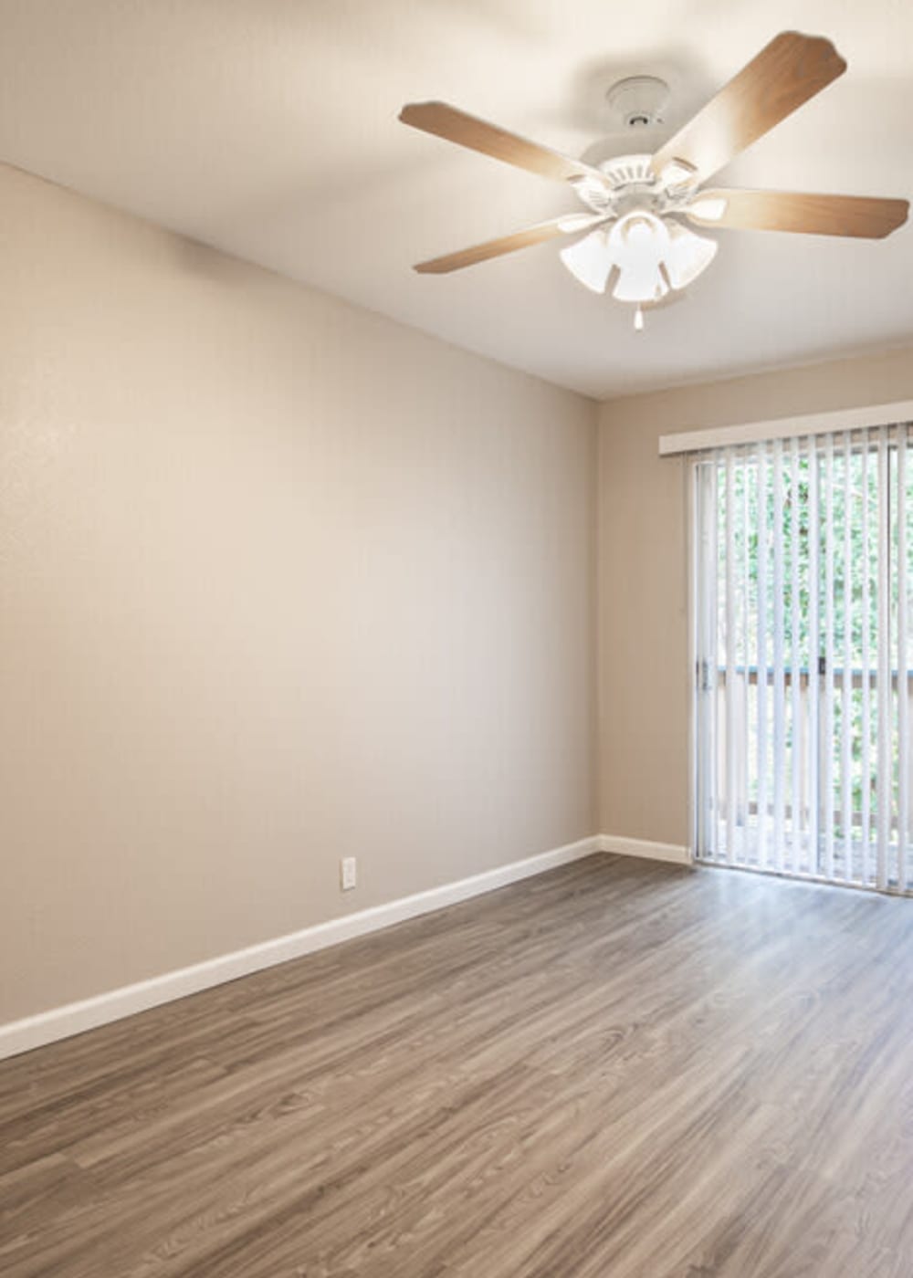 Apartments Walnut Creek, CA - Creekside Terrace - Unfurnished Living Area with Tan Walls, Sliding Door to Balcony, Ceiling Fan, and Plank Wood Flooring