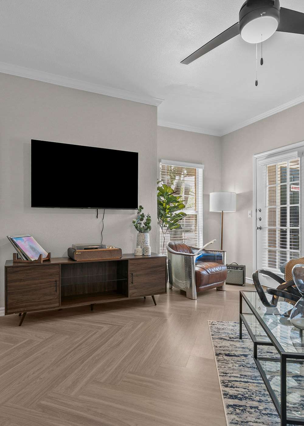 Spacious living room with a comfortable couch, large TV and a ceiling fan at Station 3700 in Euless, Texas