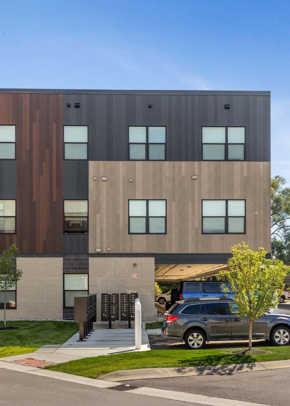 Modern apartment building with covered parking and landscaped grounds at Terra Station in Hudsonville, Michigan