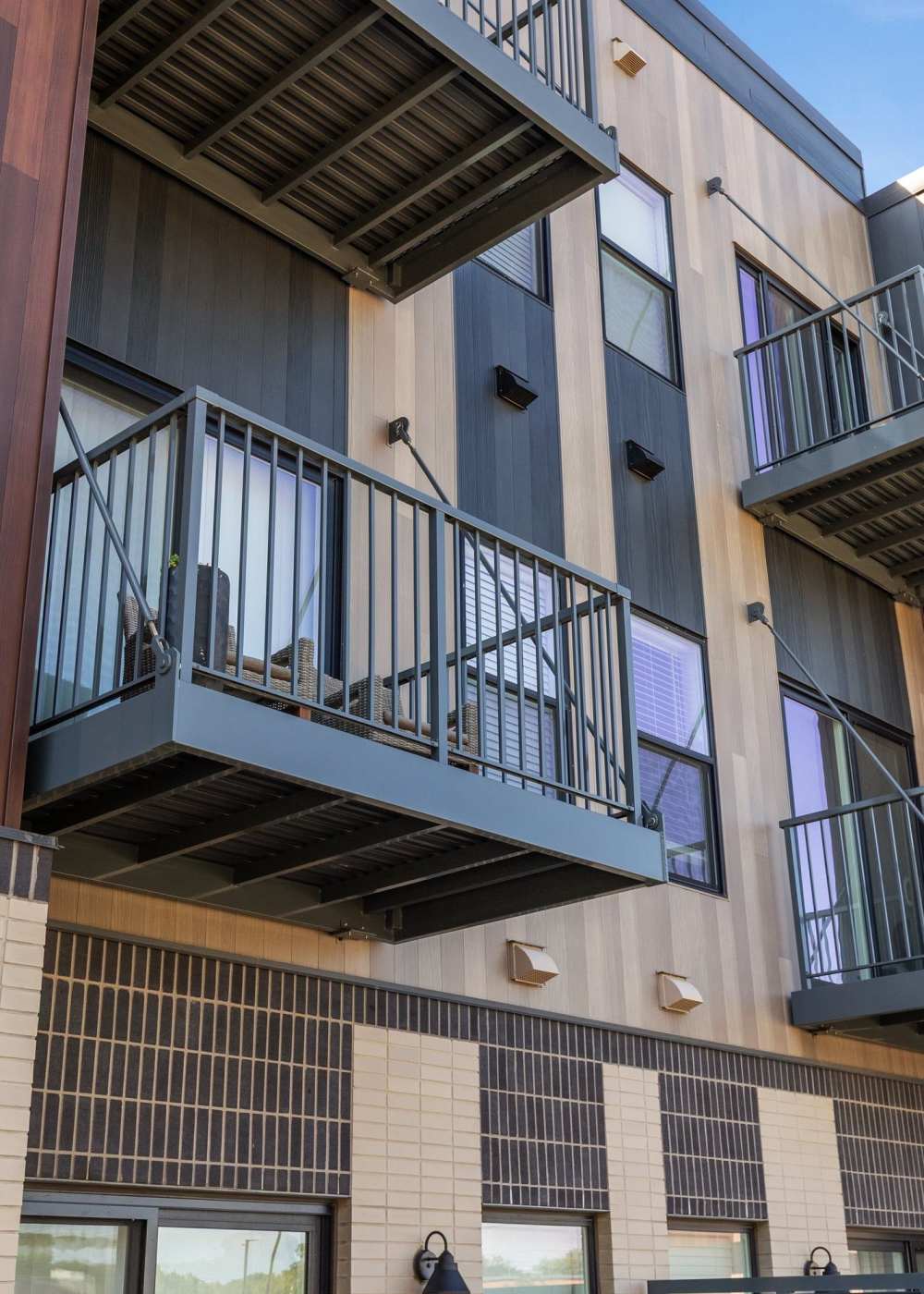 Apartment community entrance with balconies, landscaped frontage, and resident access at Terra Station in Hudsonville, Michigan