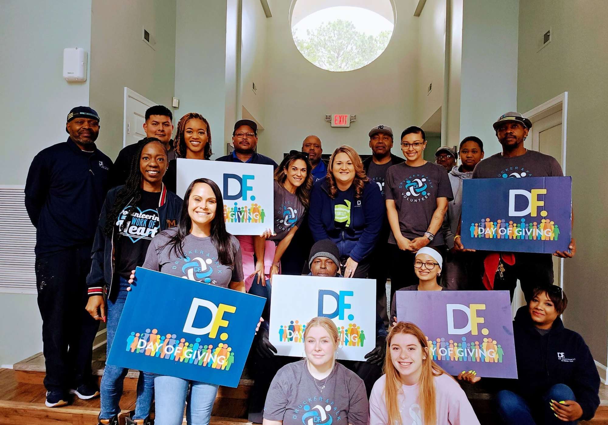 A group of people stands in a hallway, holding up various signs with messages of support and solidarity at Drucker + Falk in Newport News Virginia