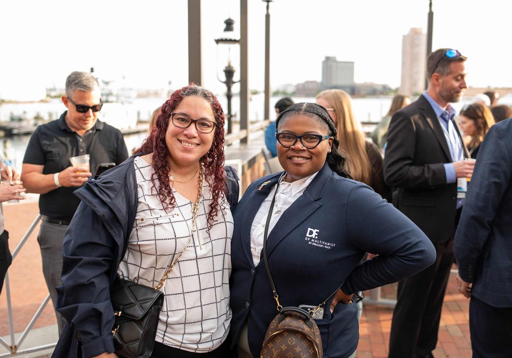 Two women standing side by side, smiling, at a social event, dressed in formal attire at Drucker + Falk in Newport News Virginia