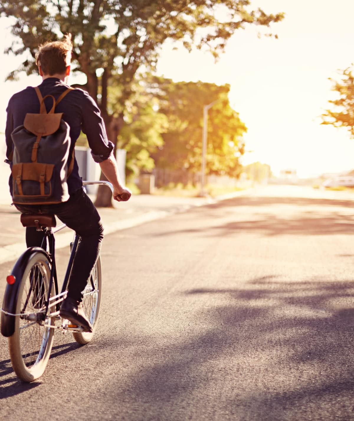 lifestyle photo of man riding bicycle down the street