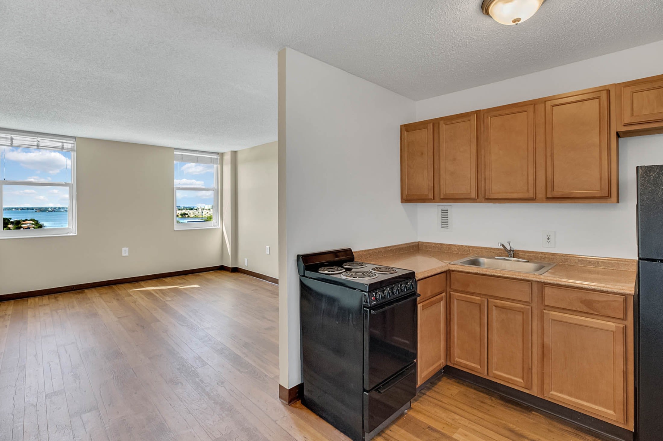 Apartment kitchen with black stove and wooden cabinets at Bay Pointe Tower in South Pasadena, Florida