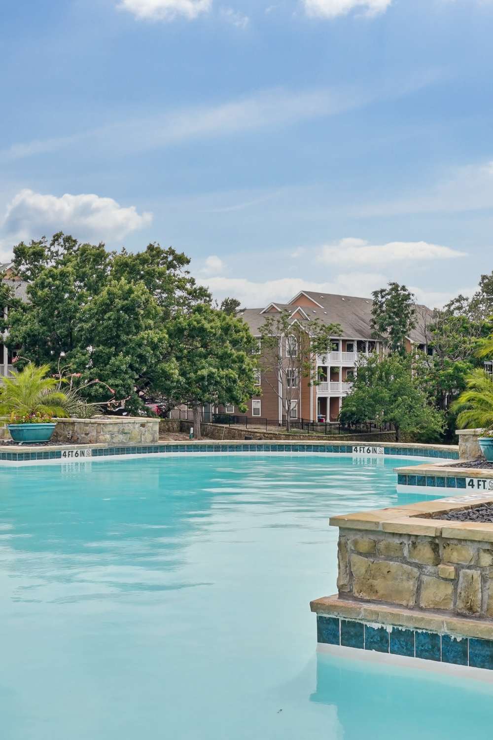 Sparkling swimming pool with lush greenery at Flatiron District at Austin Ranch, The Colony, Texas