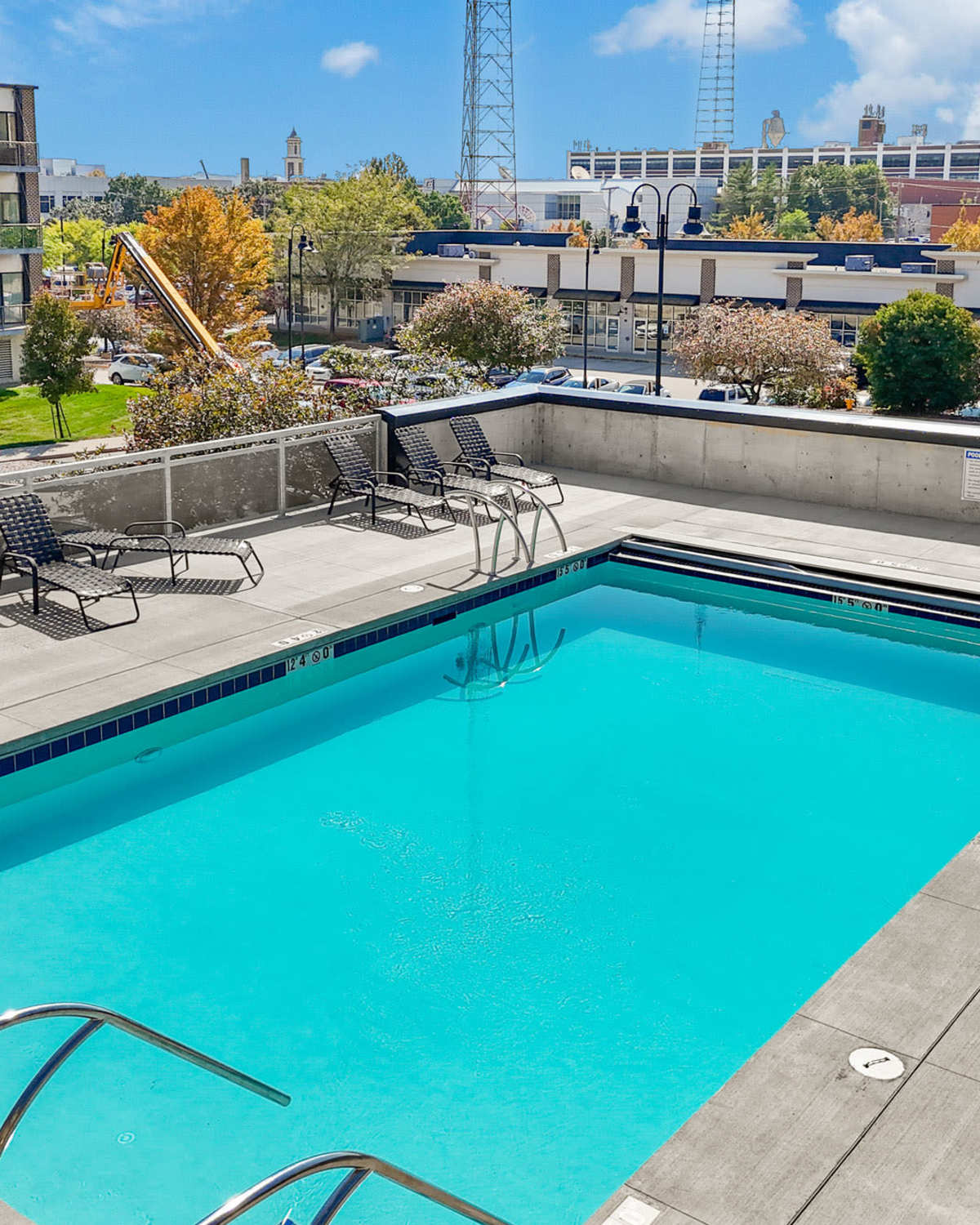 Sparkling pool with lounge chairs and landscaped area in the background at Ingersoll Square in Des Moines, Iowa