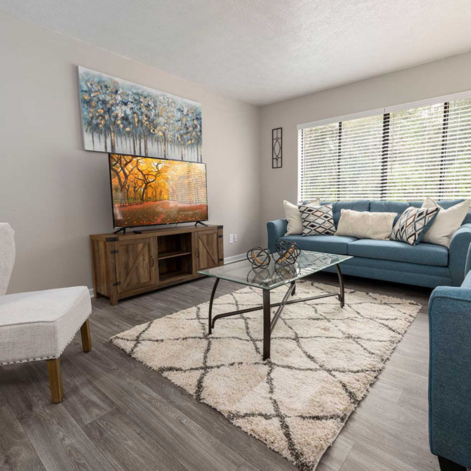 Modern furnishings and hardwood-style flooring in a model home's living space at Cross Creek in Columbus, Georgia
