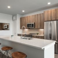 Apartment kitchen with marble counter tops and wooden cabinets at Bellrock Market Station in Katy, Texas