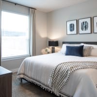 Modern furnishings in a model apartment's primary bedroom at Bellrock Market Station in Katy, Texas