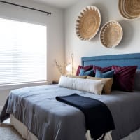 Modern furnishings in a model apartment's primary bedroom at Bellrock La Frontera in Austin, Texas