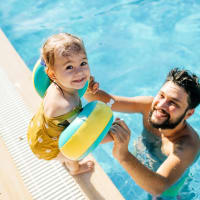 A man helping a child into the swimming pool at Mode at Owings Mills in Owings Mills, Maryland