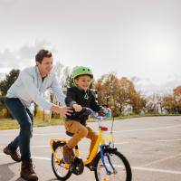 A father helping his child ride a bike at Mode at Hyattsville in Hyattsville, Maryland