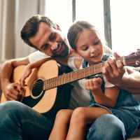 Father and child playing guitar together at Woodland Hills in Humble, Texas