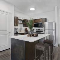 Modern kitchen with granite countertops, stainless steel appliances, island, and wood-style flooring at Canyon View Crossing in Orem, Utah