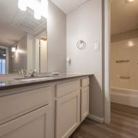 Bright bedroom with wood-style flooring, ceiling fan, and large window letting in natural light at Fairways on Thunderbird in Phoenix, Arizona