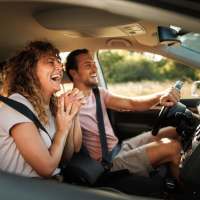 Couple laughing together in a car, enjoying a fun road trip experience at The Arcadia in Madison, Tennessee