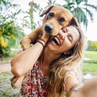 Woman smiling while holding a puppy outdoors in a lush green area at Retreat at the Park in Burlington, North Carolina