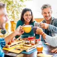 Group of friends enjoying drinks and snacks at a table near Dr. Louis A. Venson Senior Lofts in Pittsburgh, Pennsylvania