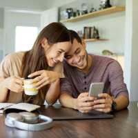 Couple enjoying coffee and phone at kitchen table Terramonte Apartment Homes in Pomona, California