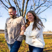 Resident couple walking outdoors along a leaf-covered path at Athena Apartments in Benbrook, Texas