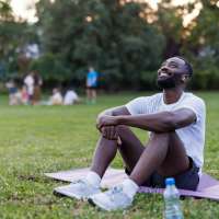 Man relaxing on yoga mat in park near August Friendswood in Friendswood, Texas