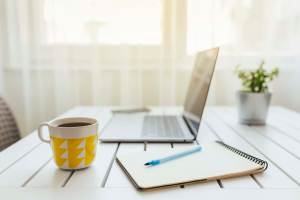 A laptop, notepad and a coffee mug placed on a table of Copper Mountain in Richland, Washington