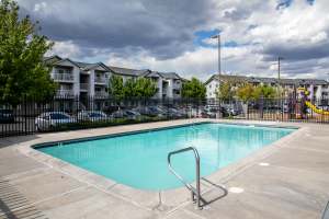 Woman reading a book, while sitting in the seating area of pool at Heron Creek Apartments in Moses Lake, Washington