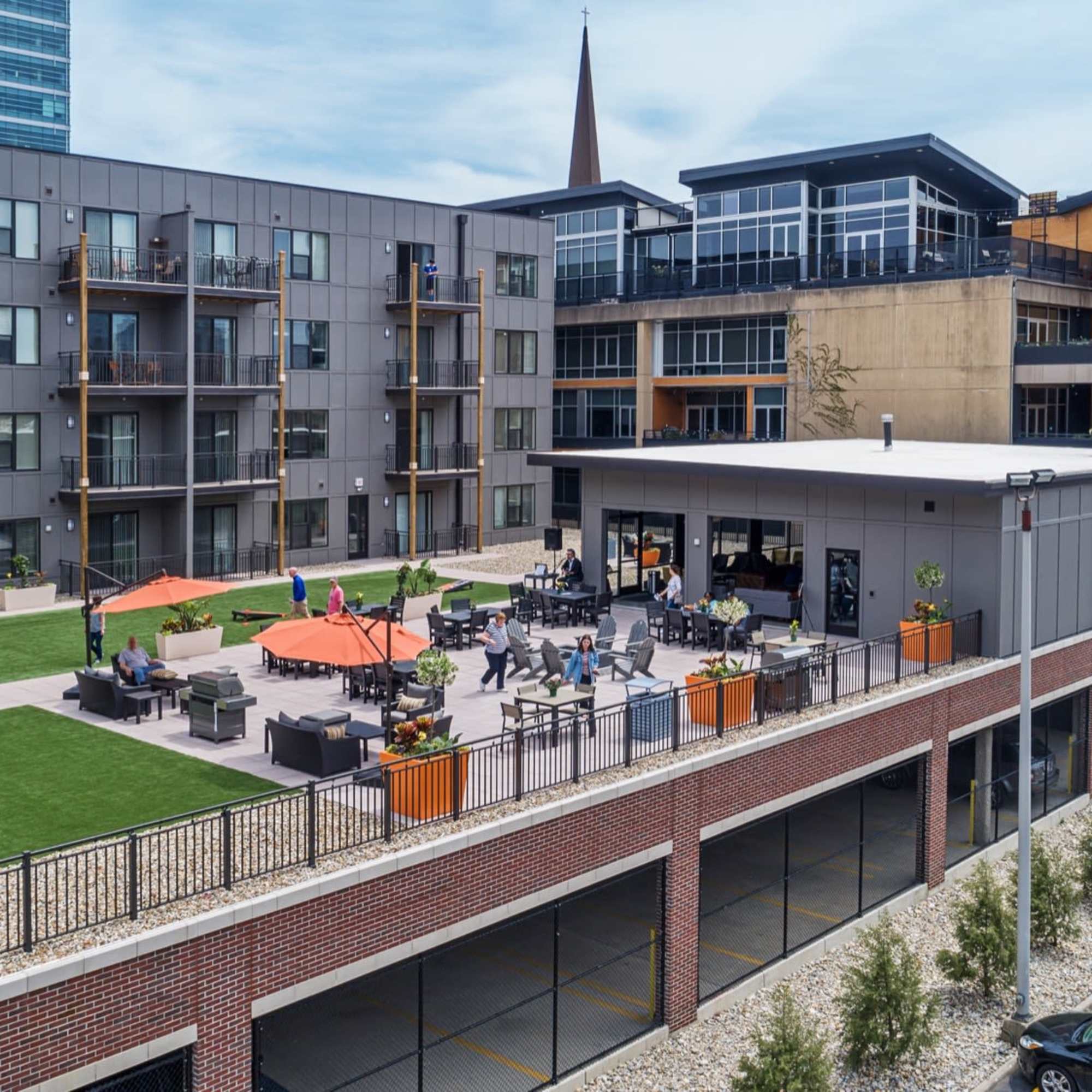 Gray buildings with orange umbrellas and seating at 223 E Town in Columbus, Ohio