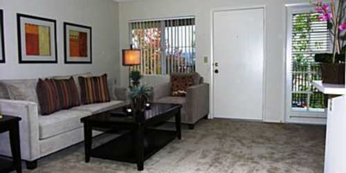 A furnished apartment living room with a large window at Country Views Apartments in Fallbrook, California