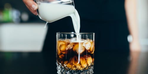 Milk being poured into a glass of coffee at Somerset Apartments in Martinez, California