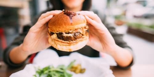 Woman eating burger near Curtis Johnson in Los Angeles, California