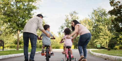 parents helping their kids riding bike in park near Academy Lane Apartment Homes in Davis, California