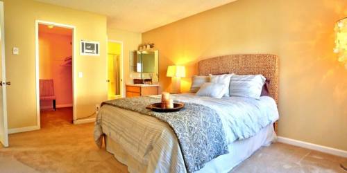 Spacious bedroom with large comfortable bed and lamp at Countryside Apartments in Poway, California