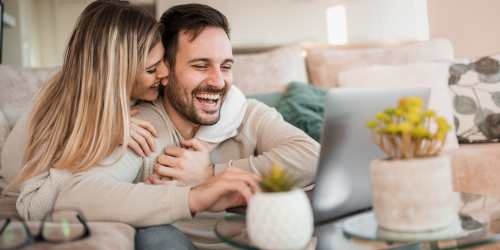 A couple laughing and embracing on their couch at Hawk's Landing in Fort Myers, Florida