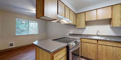 Kitchen with multiple wooden cabinets and granite countertop at Heron Hills Apartment Homes in Gresham, Oregon